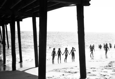 Models holding hands on the beach.